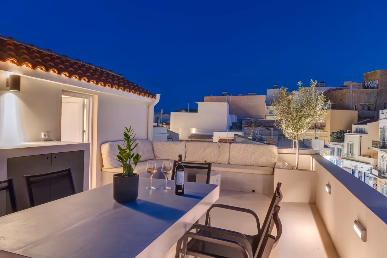 Upper terrace dining table at night overlooking Ermoupolis
